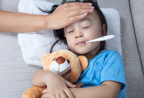 sick child with thermometer in mouth and nurse hand on forehead